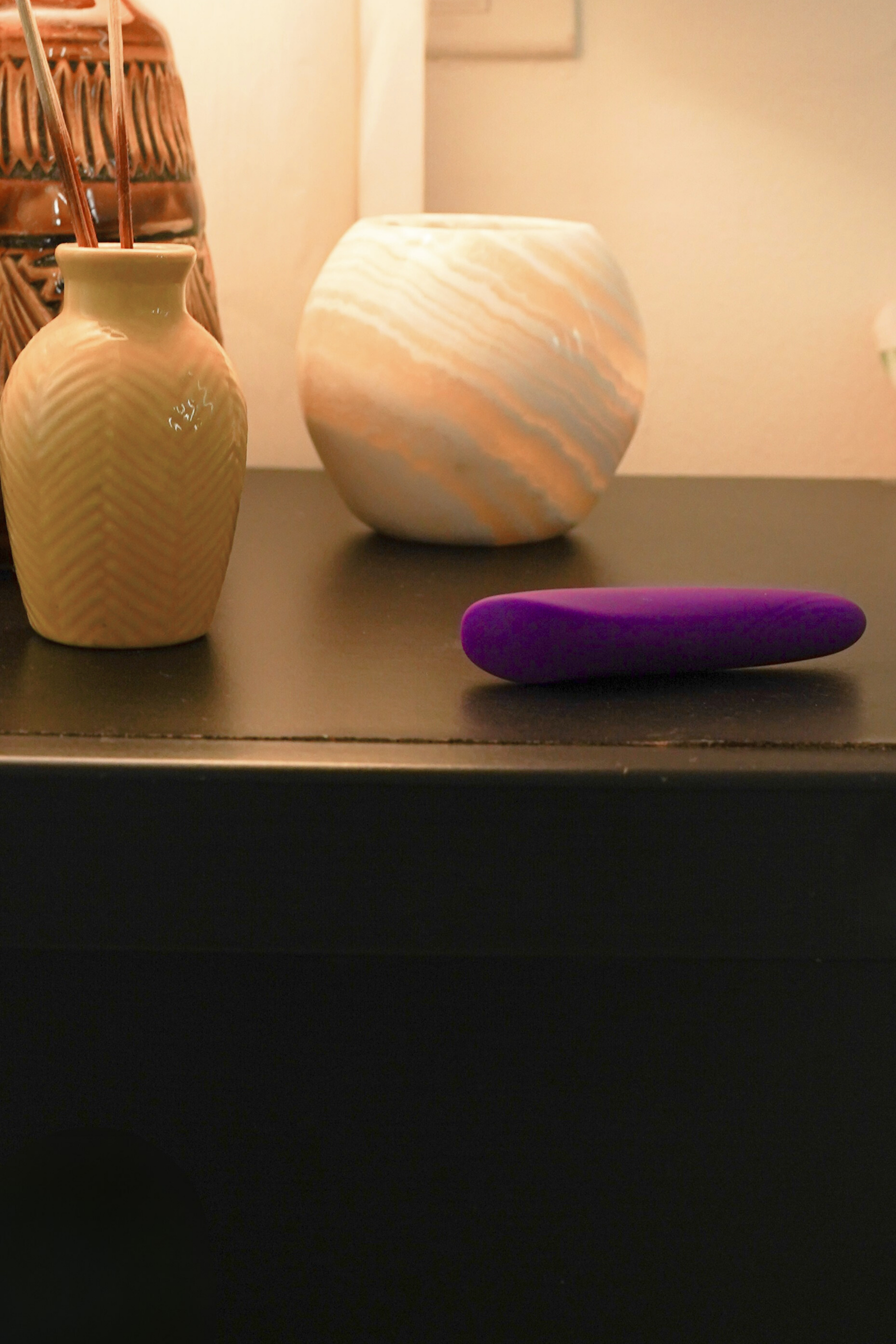 Purple bullet massager on a bedside table, premium and relaxing atmosphere relating to wellness